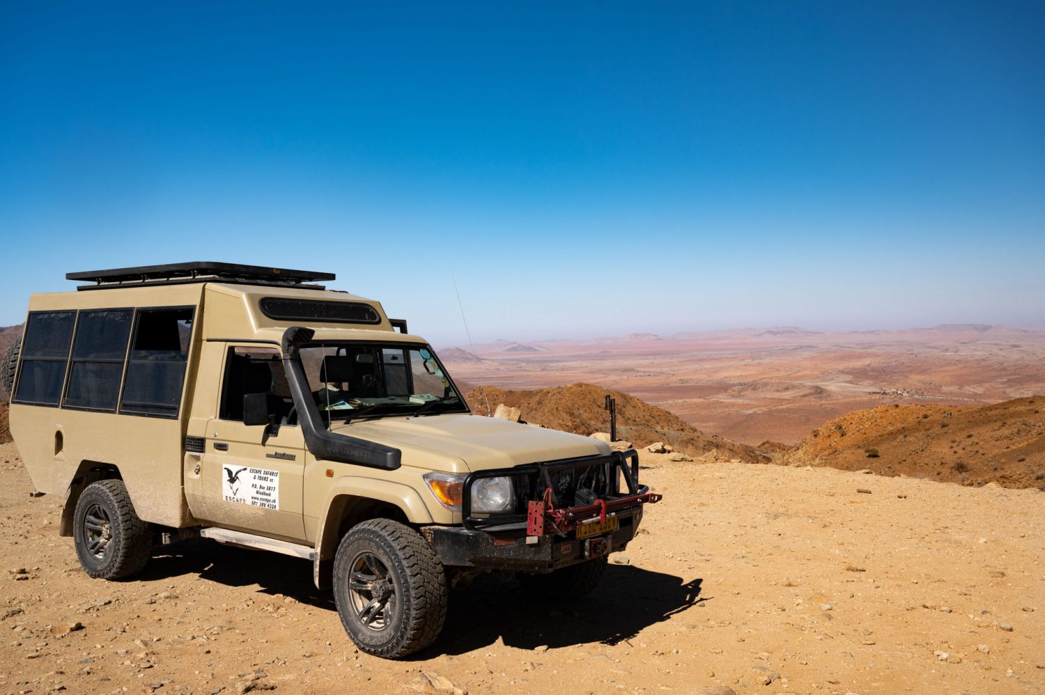 Offroad-Fahrzeug parkt auf Aussichtspunkt, Wüstenlandschaft im Hintergrund